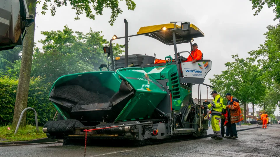 Schulungsteilnehmer in Warnwesten bei der Einweisung an der Baumaschine