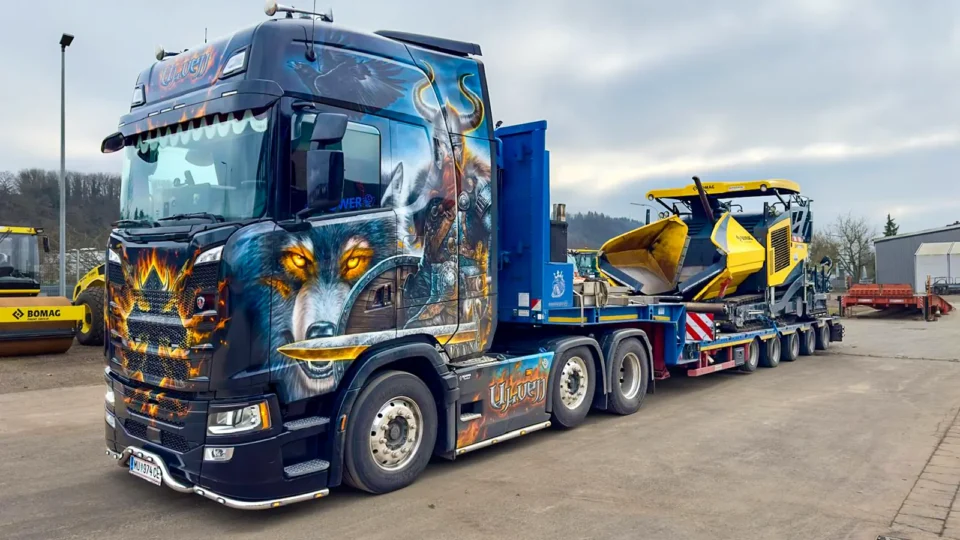 Schwerlast-LKW mit Tieflader transportiert eine Baumaschine