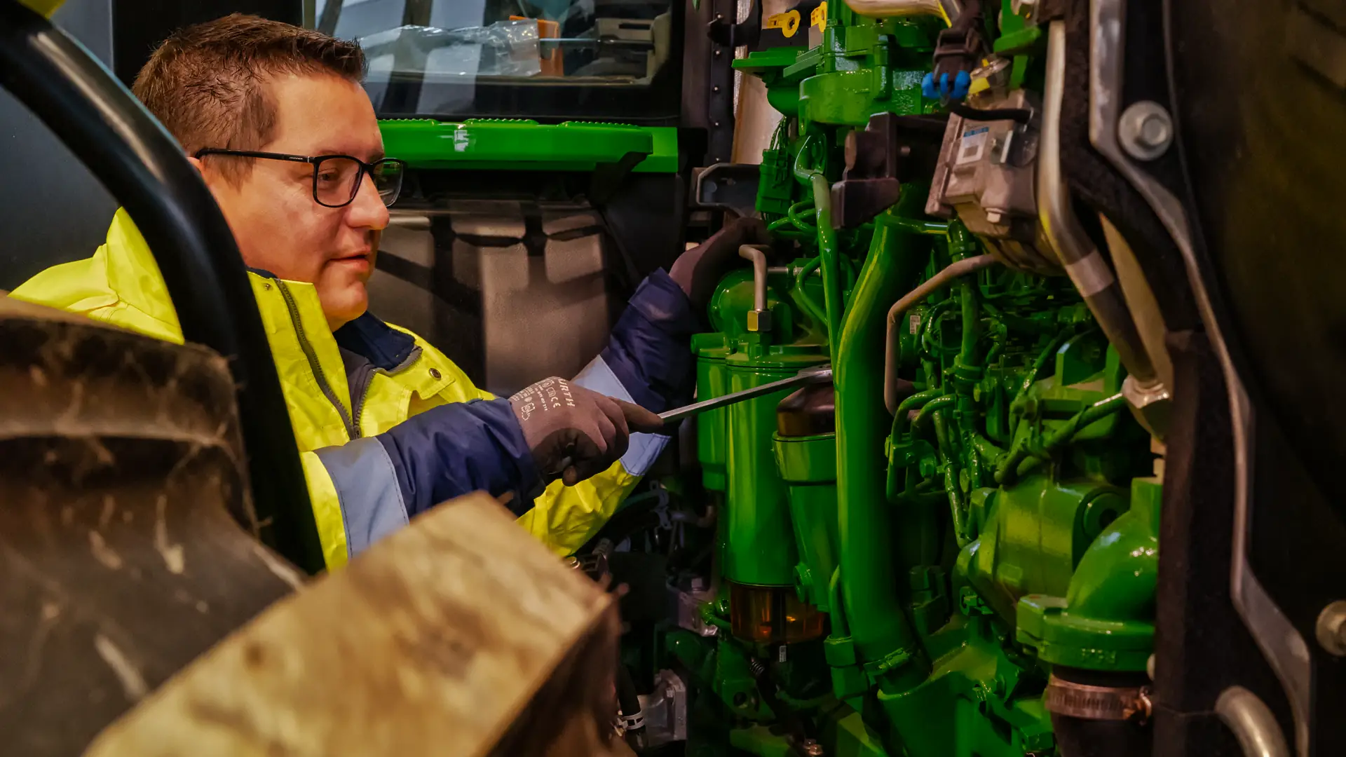 Mechaniker arbeitet im Technikraum einer grünen Baumaschine